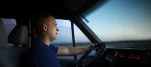 A man focused on driving, illuminated by a sunset