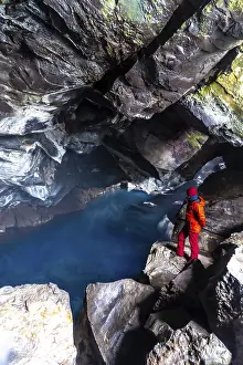 A man in the Grjotagja volcanic cave with hot thermal water near Lake Myvatn