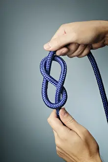 Man holding blue rope with figure of eight knot in his hands