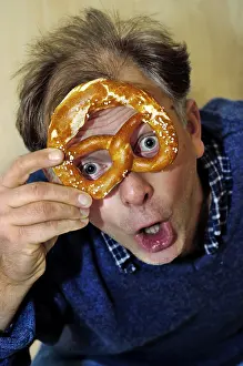 Man is looking astonished through a pretzel