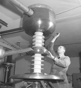 Man and machine in the 1940s. A man is seen in a room with a unusual techical construction of unknown purpose