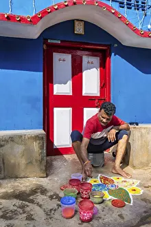 Man making a Mandala with colored sand in front of his house