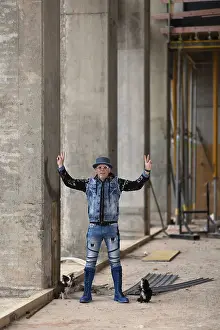 Man in modern jeans clothing with hat posing on a construction site between columns
