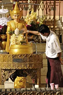 Man pouring water over a Buddha statue