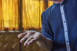 Man showing silk thread coming from a silk worm cocoon in a silk factory