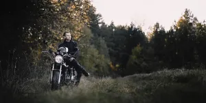 Man sits on a motorcycle in a forest