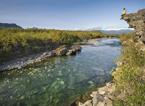 Man sitting on stone cliff over the river Abiskojakka