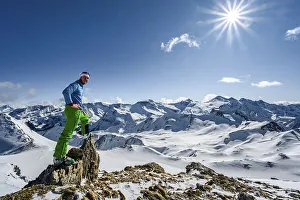 Man, ski tourer looks over snow-covered mountain ranges
