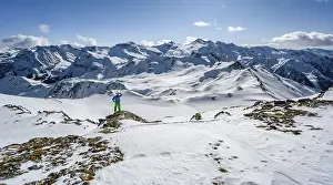 Man, ski tourer looks over snow-covered mountain ranges