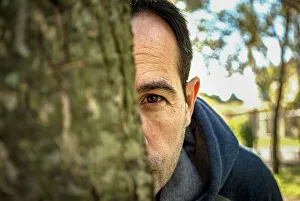 A man spying behind a tree