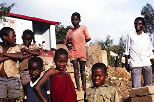 Man standing with a group of boys carrying bricks for him, Malawi, southern Africa 1991, Africa