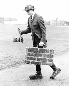 Man with suitcase, shoes and camera made of bricks
