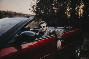 Man with sunglasses lounges in a red convertible