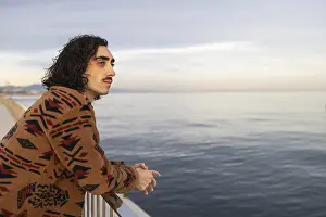 A man with a thoughtful expression leans against a railing