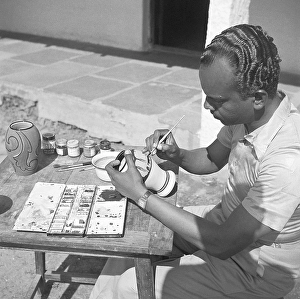 Man using portable rotating lathe applying lacquer to a wringtinforia wood, painting lacquer toys, Channapatna, Karnataka