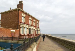 Man walking past historic houses on the seafront
