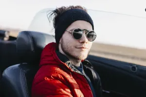 Man wearing sunglasses and a red jacket in a convertible