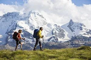 Mountaineering Prints: A man and a woman hiking, Schweifinen Plateau at the back the mountains Breithorn and Klein Matterhorn