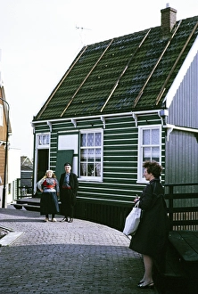 Man and woman in traditional dress standing in front of a village house, Mark, Netherlands, 1973