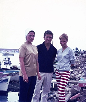 A man and two women fashionably dressed standing next to boats on holiday in Spain, 1966
