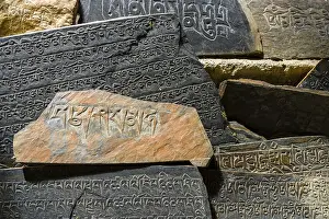 Category Buddhism Prints: Mani stones with the engraved tibetan mantra Om Mani Padme Hum are piled up to a wall