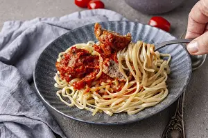 Man's hand holds a fork with pasta and meatball<br> Man's hand holds a fork with pasta and meatball