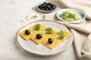 Marble cheese with olives and watercress microgreen on gray concrete background and linen textile