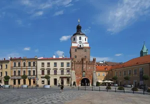 Market square with historic city gate and surrounding buildings under a blue sky