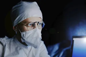 Masked professional in dark, illuminated by blue light