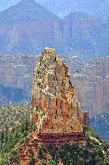 A massive rock rises steeply in a canyon landscape