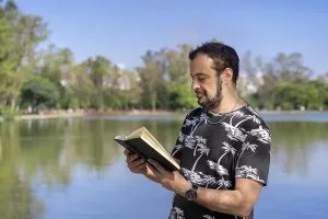 Mature man reading by a lake, enjoying free time on a sunny day