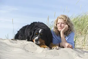 Mature woman with her dog on sand and grass