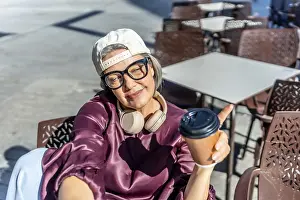 Mature woman with gray hair and glasses wearing a cap and headphones
