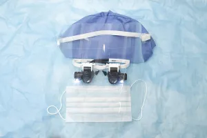 Medical equipment including mask and cap on blue background