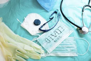 Medical items on blue fabric include gloves and COVID-19 mask