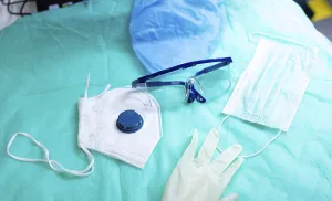 Medical mask, gloves, and goggles on a blue surface