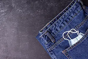 A medical mask peeks out of a jeans pocket