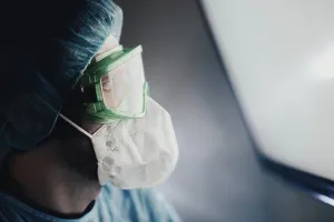 A medical professional in protective gear looking intently outside of the frame