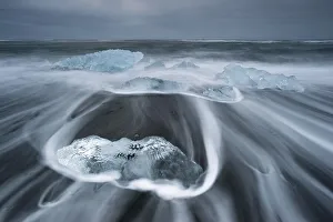 Melting icebergs lying in the strong surf on the black volcanic beach at Joekulsarlon