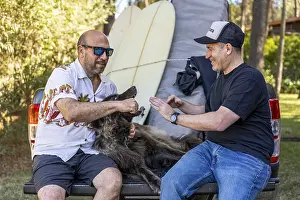 Two men and their dog relaxing on a pickup truck