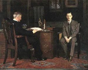 Two men are in an office, one sitting at a desk and the other on a chair