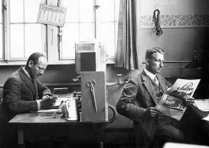 Two men in the office, one working