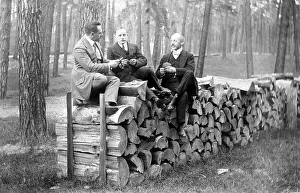 Men sitting on a wood pile, historical photo