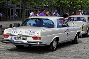 Mercedes Benz 280 SL, white vintage Mercedes car on a paved road with spectators in the background