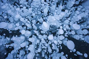 A mesmerizing view of numerous frozen bubbles captured in a thick layer of ice on a lake