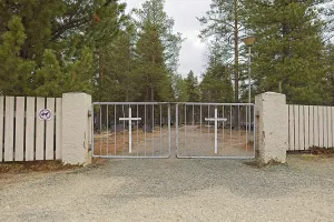 Metal cemetery gates with a cross in cloudy spring weather