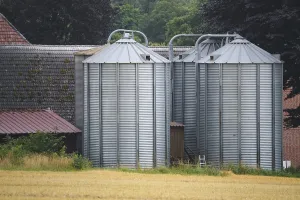 Metal silos storing harvested crops on a farm in a rural landscape