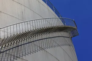 Metal staircase winds around a large tank in an industrial environment