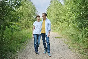 A middle-aged couple enjoys a stroll along a gravel path shaded by lush greenery