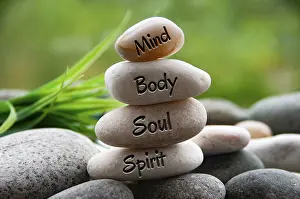 Mind, Body, Soul and Spirit words engraved on zen stones with blurred nature background